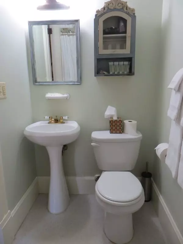 Private bathroom in the Yogi Berra Suite with pedestal sink, toilet, and mirror