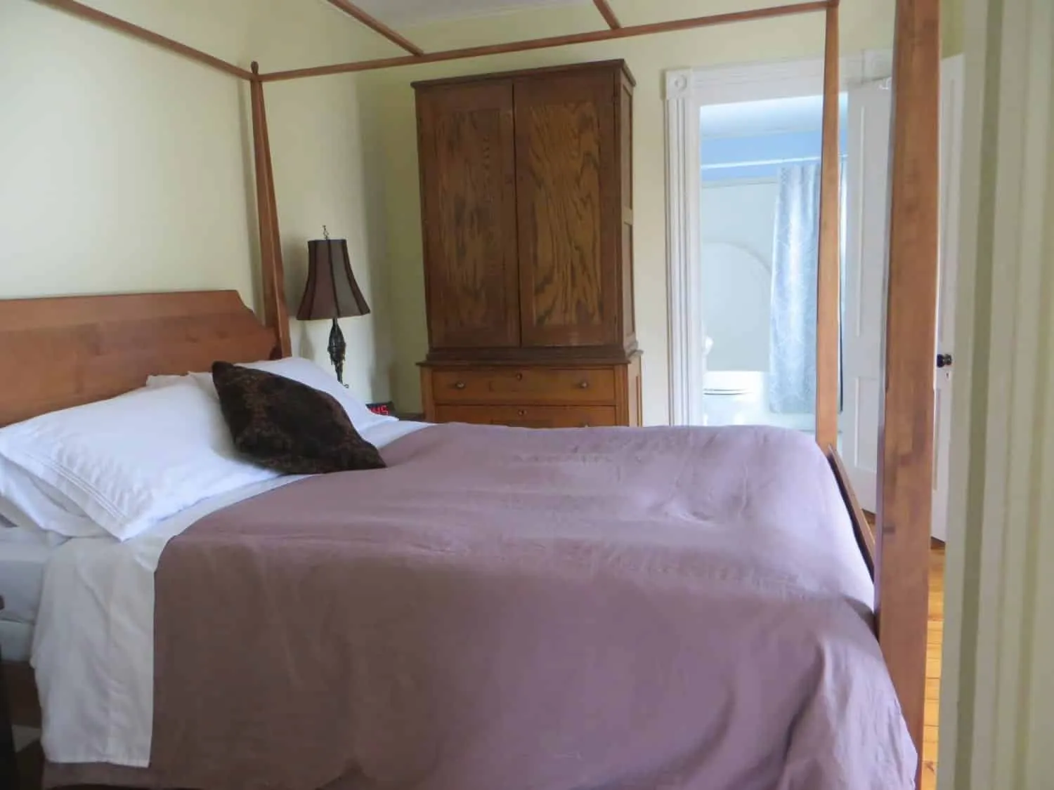 Queen bed in the Ozzie Smith Room with wood floors and doorway to the private bathroom