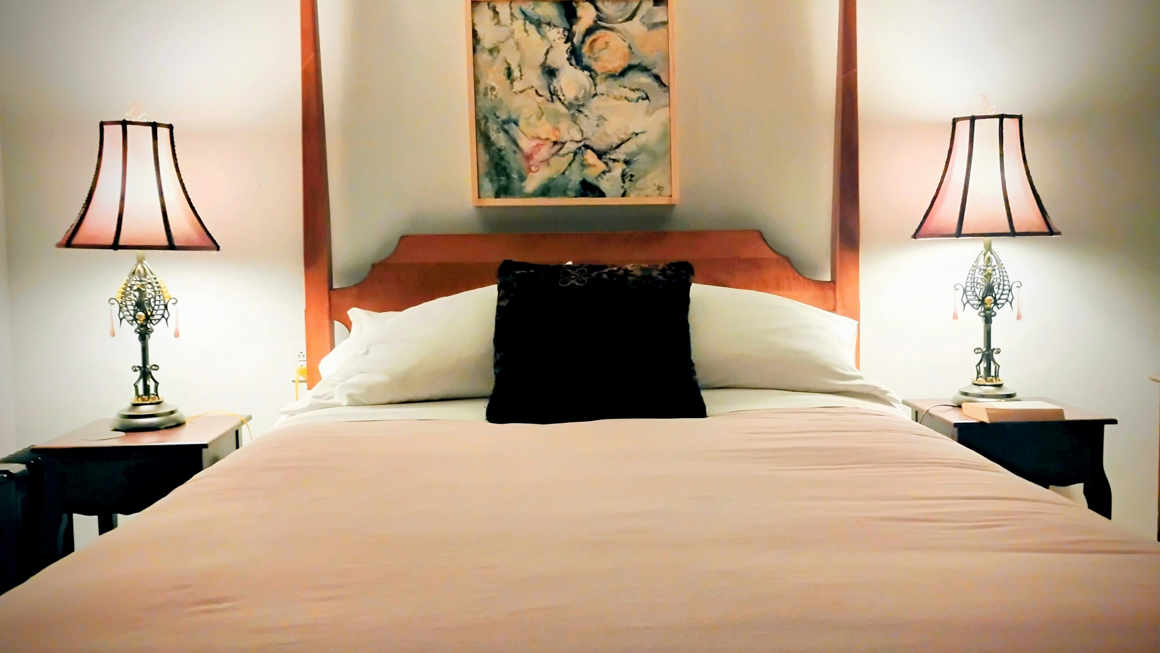 Queen bed in the Ozzie Smith Room with wood floors and doorway to the private bathroom