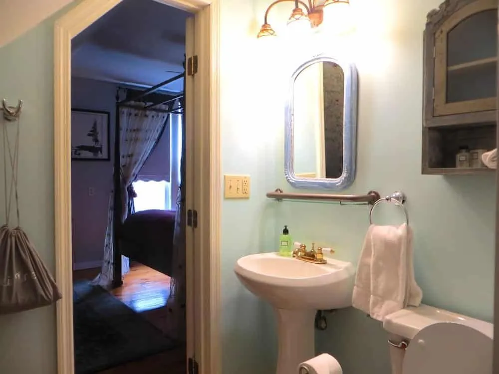 Private bathroom in the Carmen Suite with pedestal sink, mirror, toilet, and shower entrance
