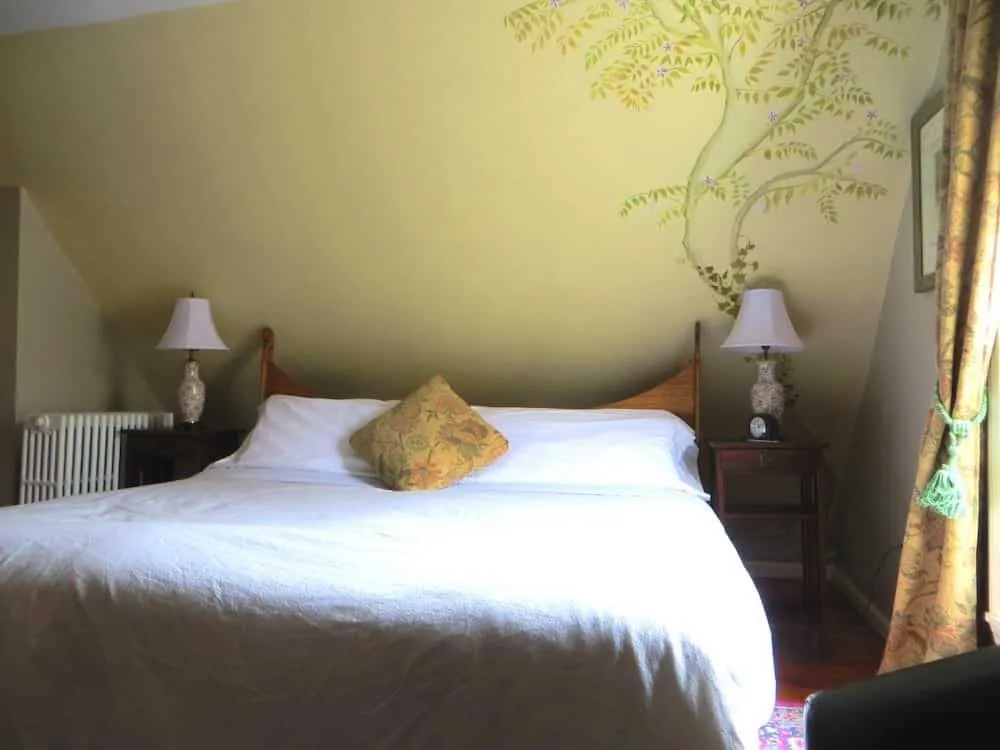 King bed in the Tosca Suite with bedside tables, lamps, and sloped ceiling