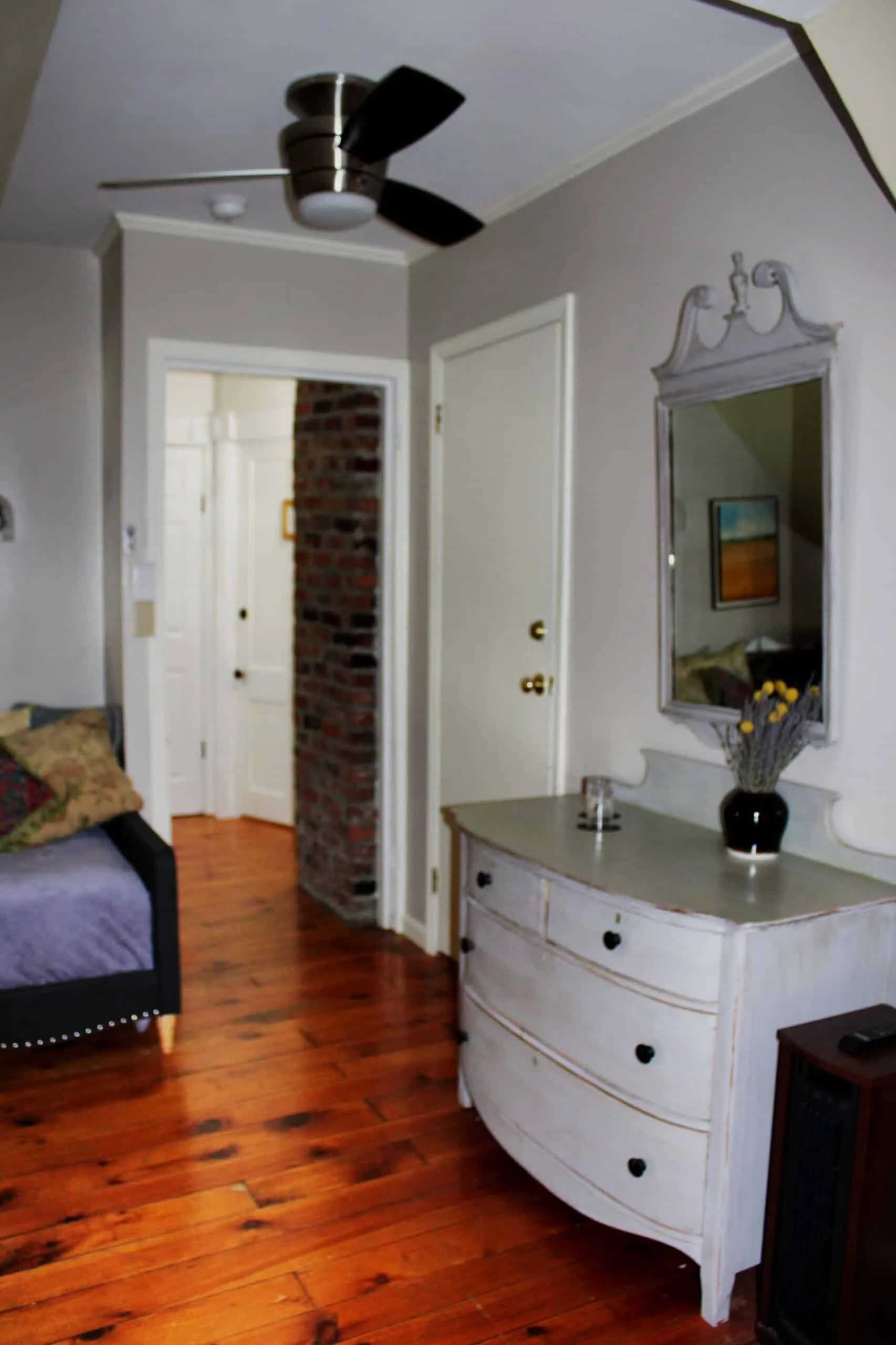 Dresser and entry area inside the Tosca Suite with wood floors and ceiling fan