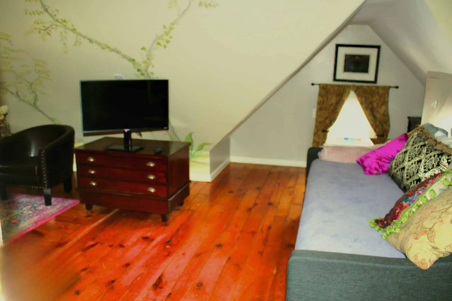 Seating area in the Tosca Suite with sofa, television, and historic wood floors