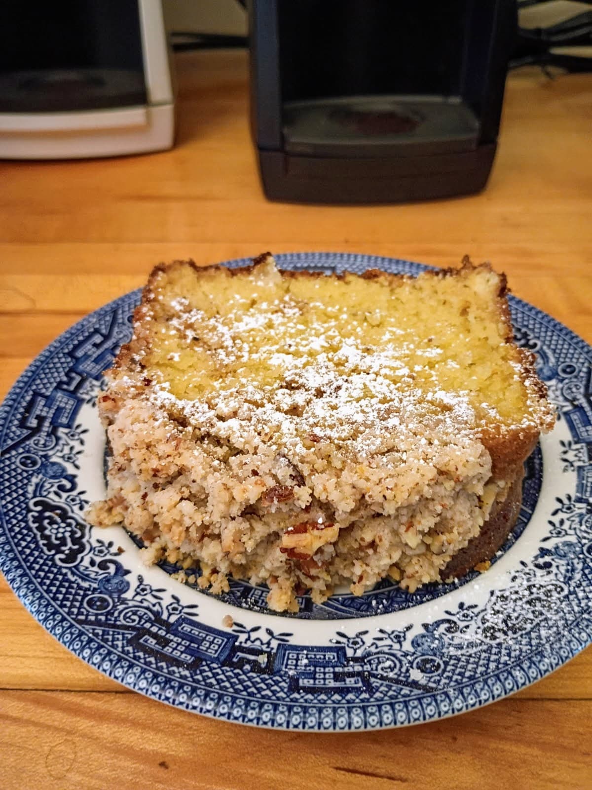A slice of baked dessert dusted with powdered sugar on a blue and white plate.