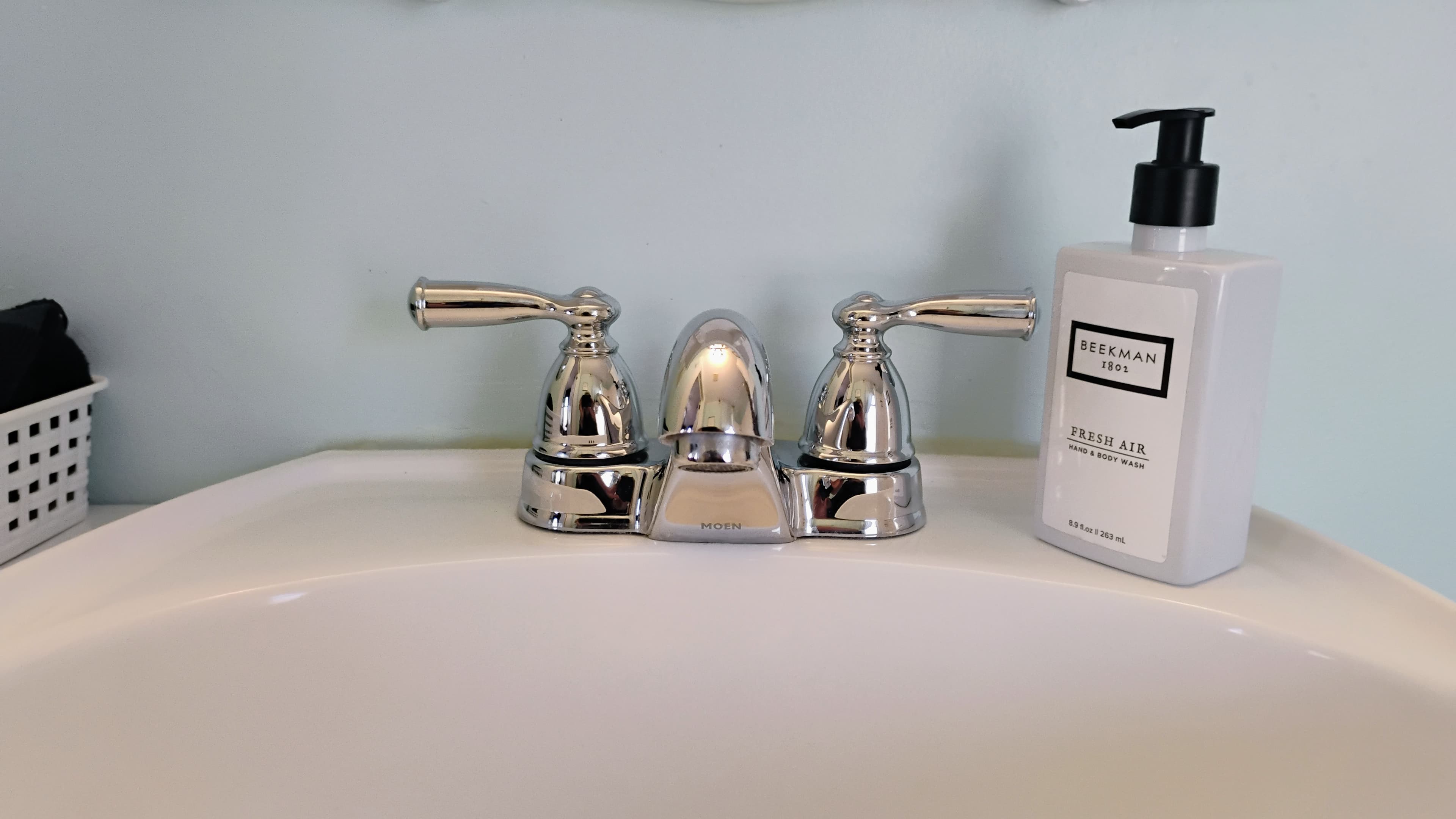 A chrome faucet set and a bottle of hand soap on a bathroom sink.