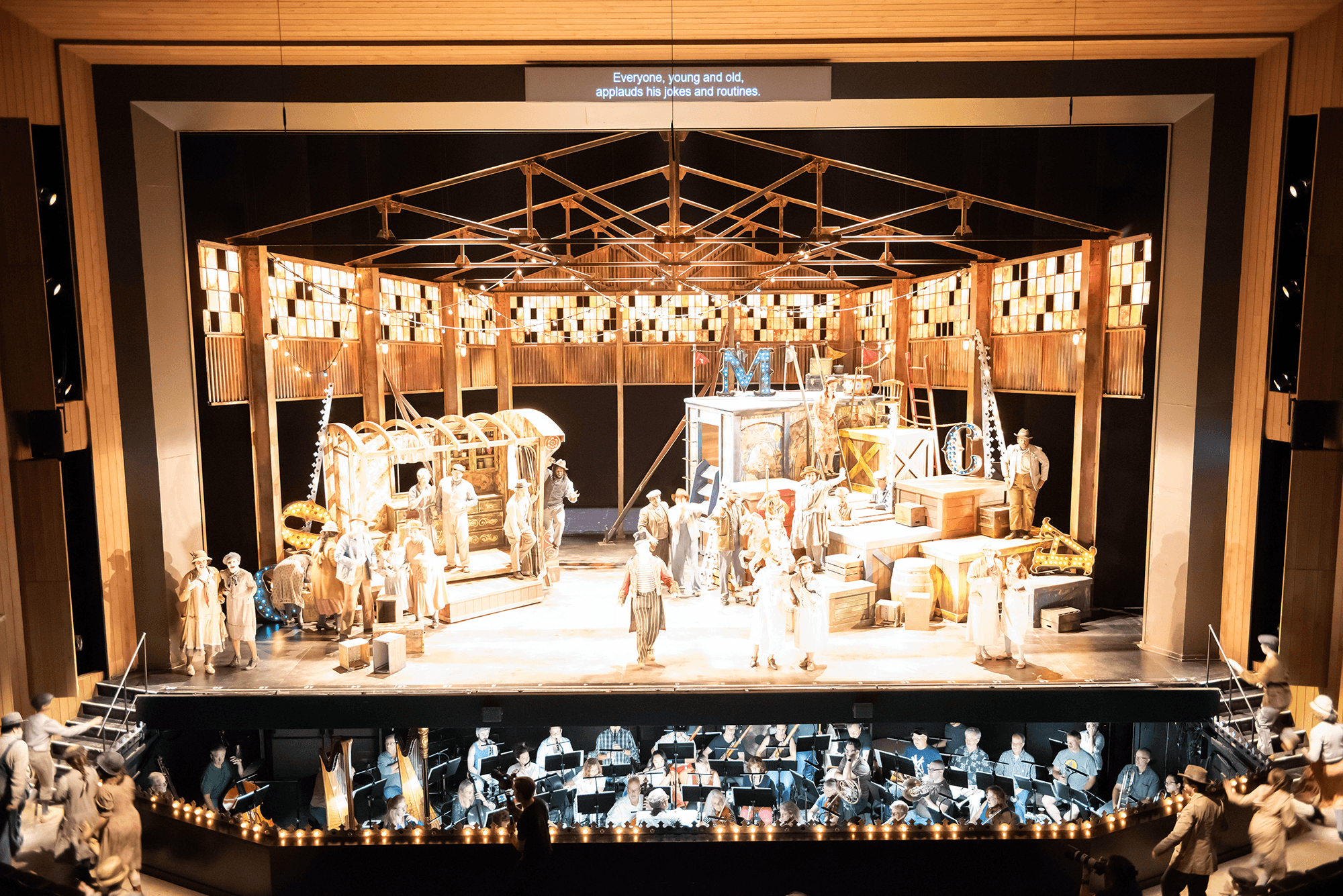 A theatrical stage featuring a performance with a large cast and a detailed set.