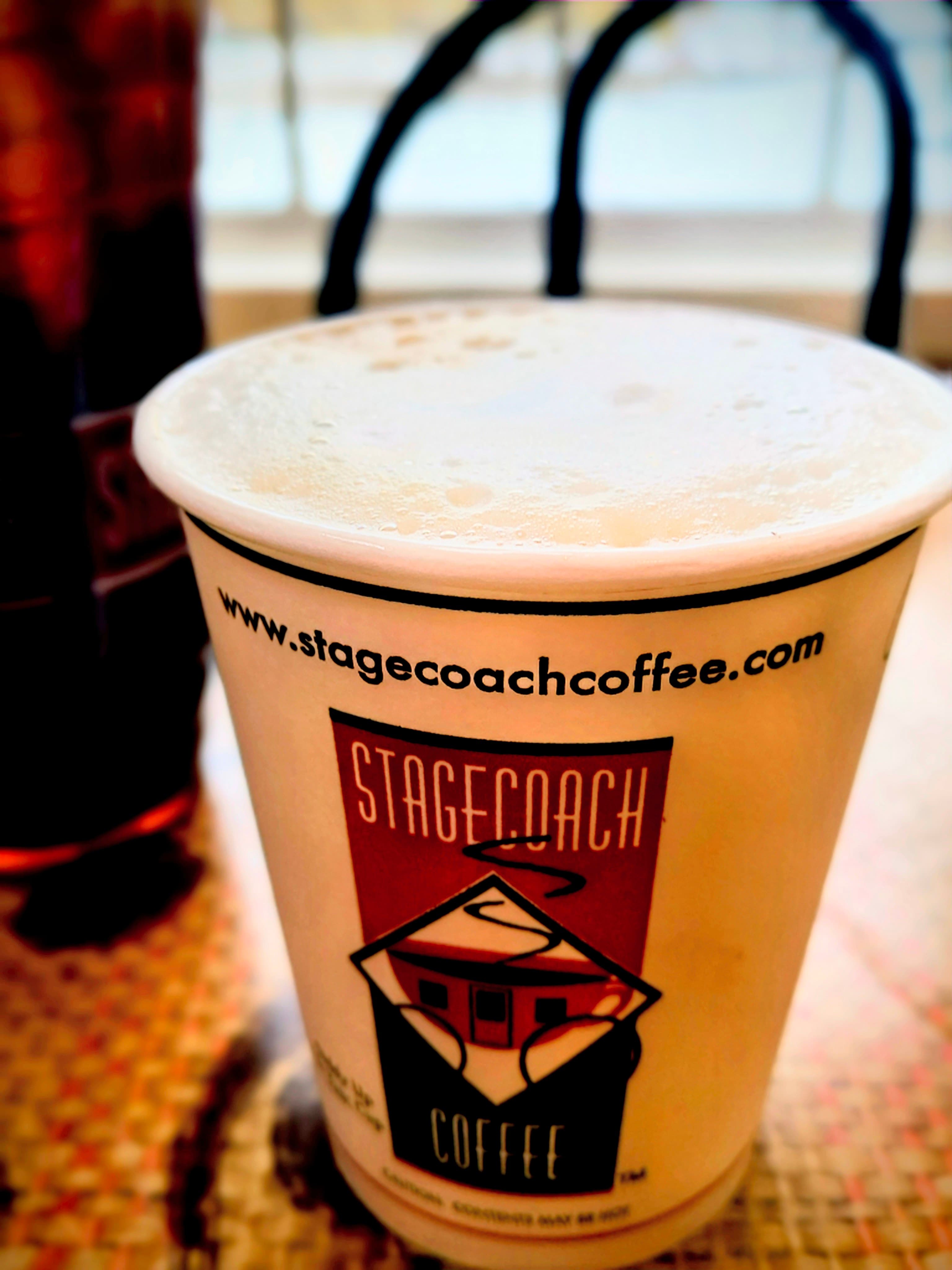 A coffee cup from Stagecoach Coffee with frothy milk on top.