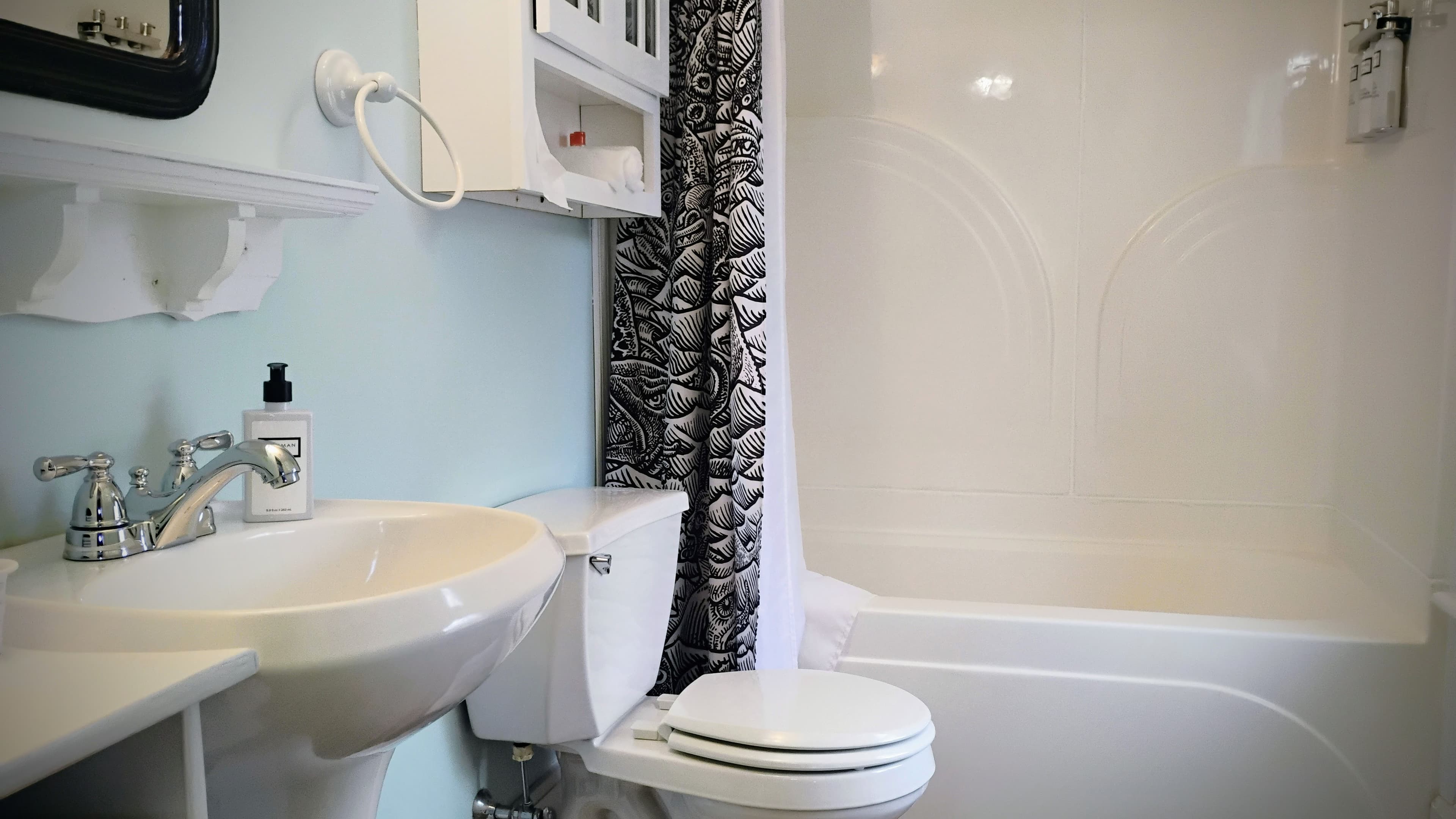 A clean bathroom featuring a sink, toilet, shower, and decorative curtain.