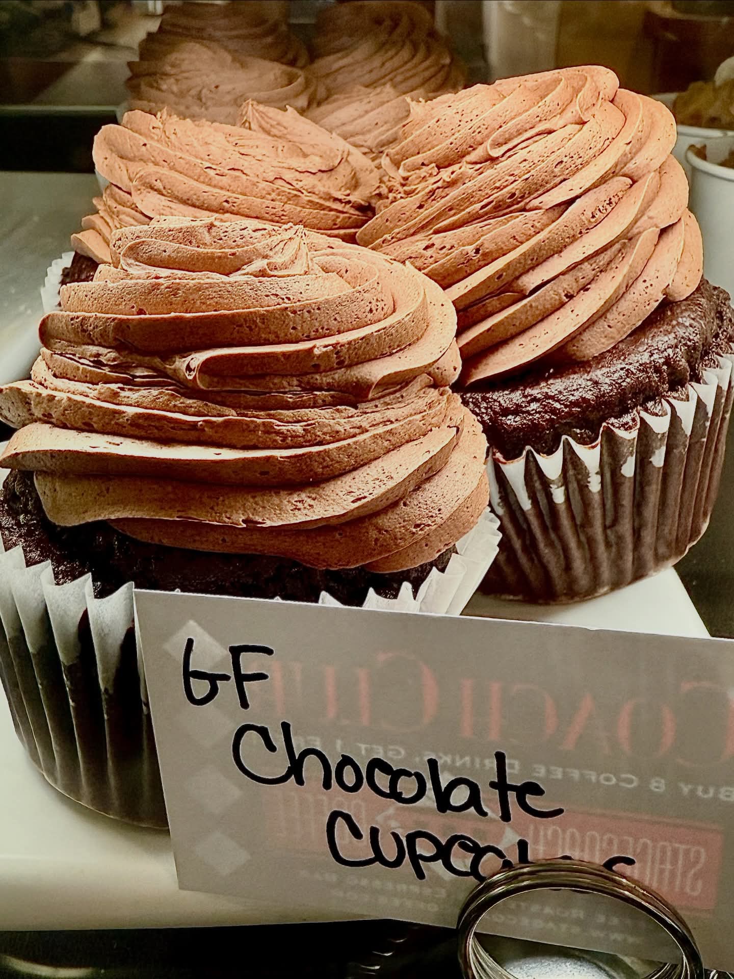 Two chocolate cupcakes with swirled frosting and a label reading "GF Chocolate Cupcakes."