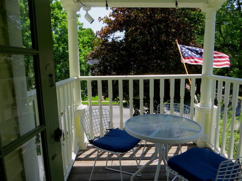 Tables and chairs on upstairs porch, with flag